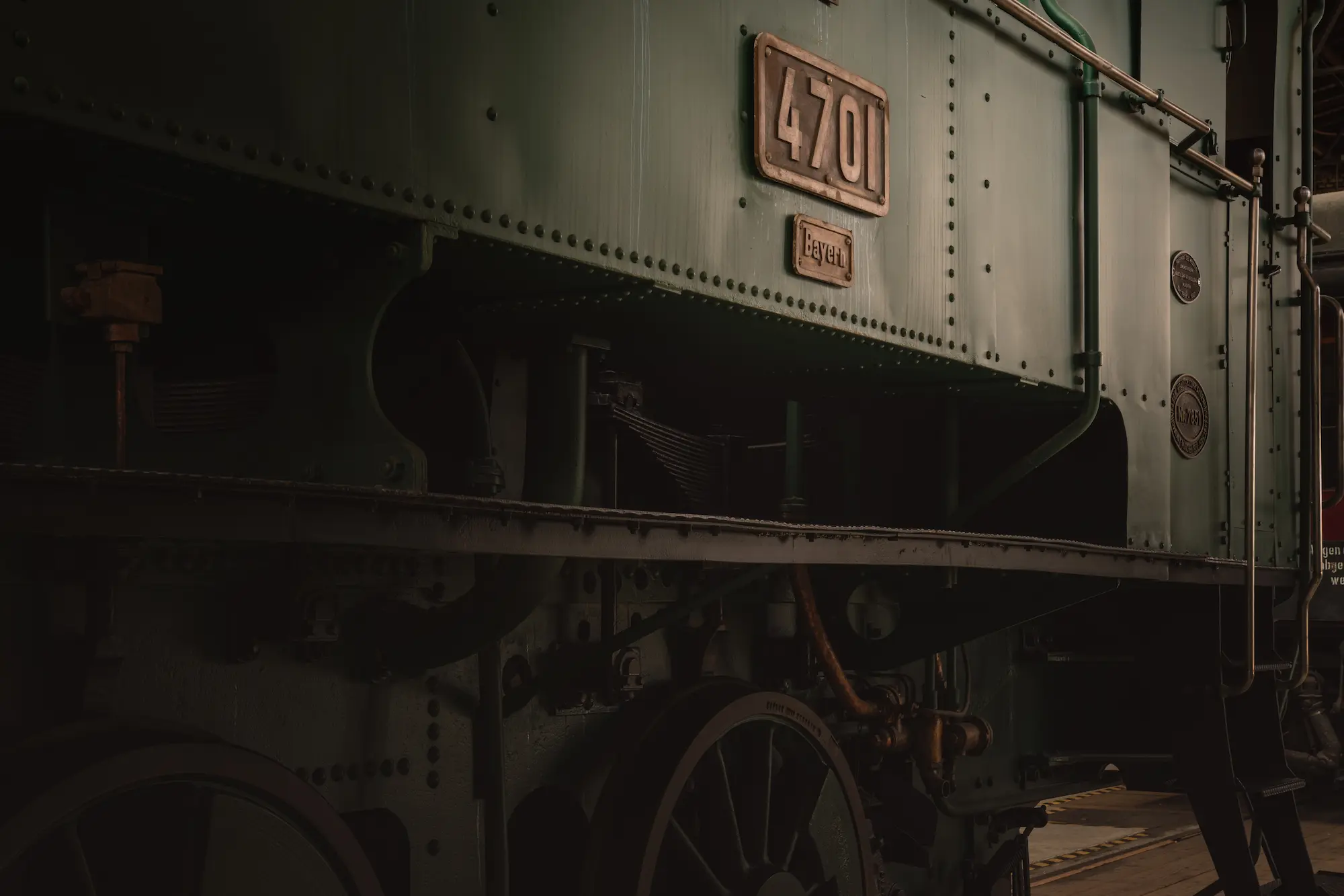 Detailaufnahme der grün-schwarzen Seite eines historischen Dampflok-Kessels im DB Museum, mit sichtbaren Nieten, Rädern und der Nummerntafel 4701.