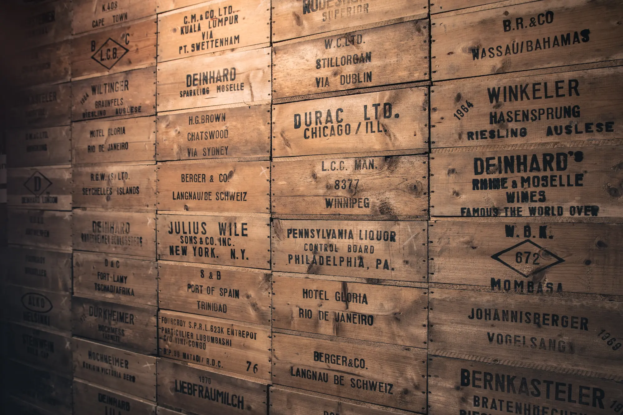 Nahaufnahme einer Wand aus historischen hölzernen Sektkisten mit Beschriftungen von internationalen Versandzielen.
