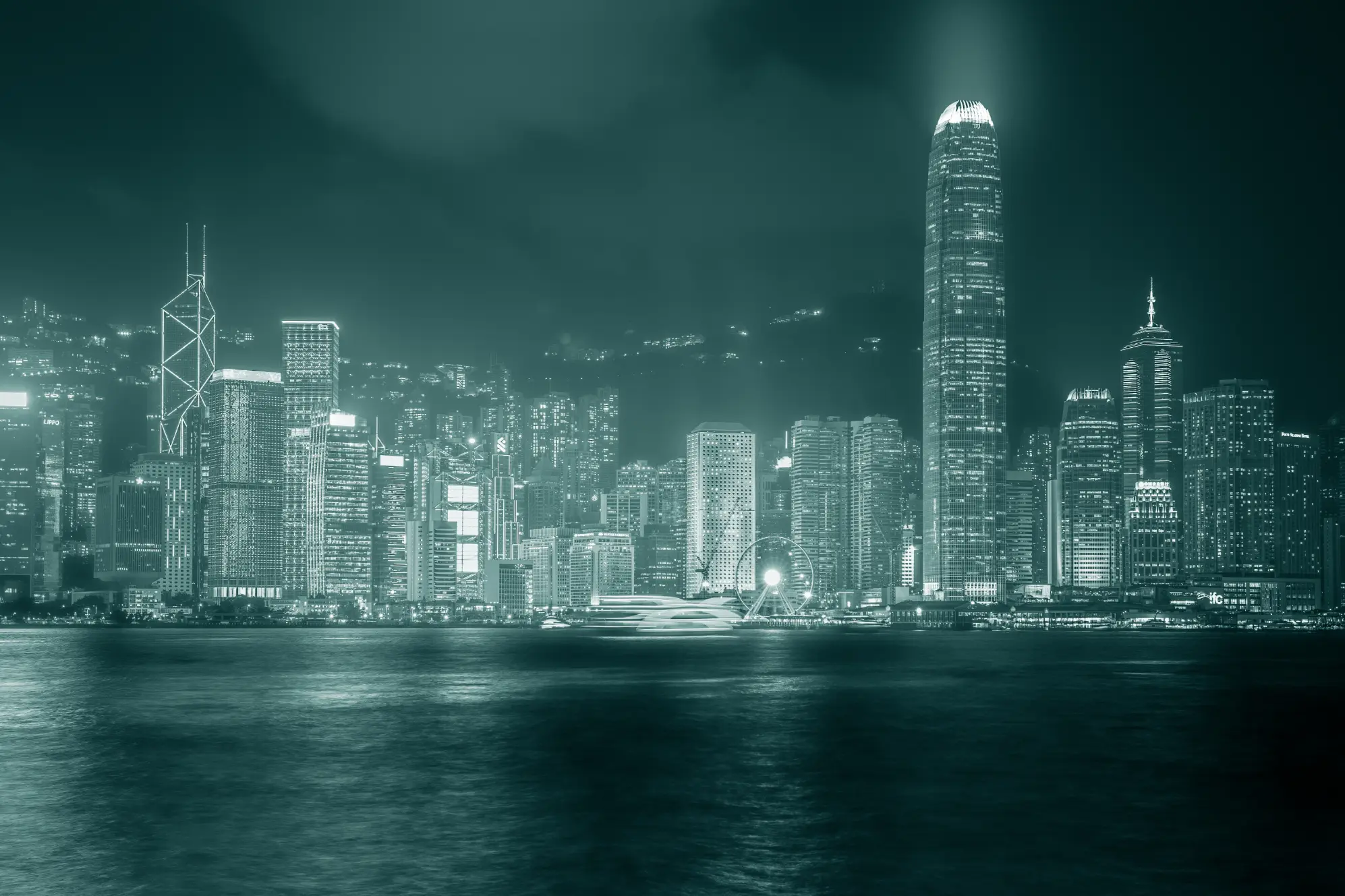 Nächtliche, monochromatische (türkis-grüne) Ansicht der beleuchteten Skyline von Hongkong mit Wolkenkratzern und dem Victoria Harbour.